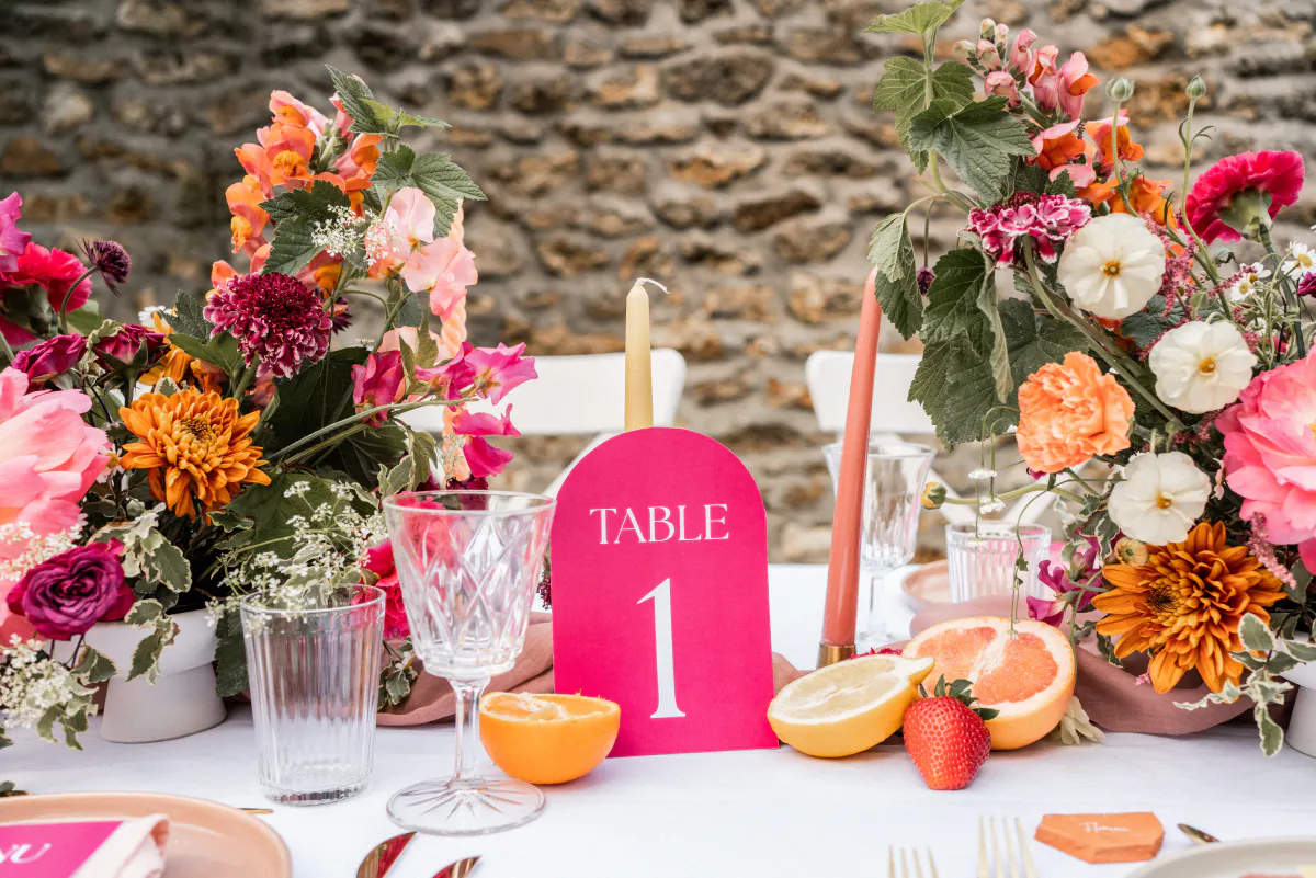 Centre de table aux fleurs vives et numéro de table rose