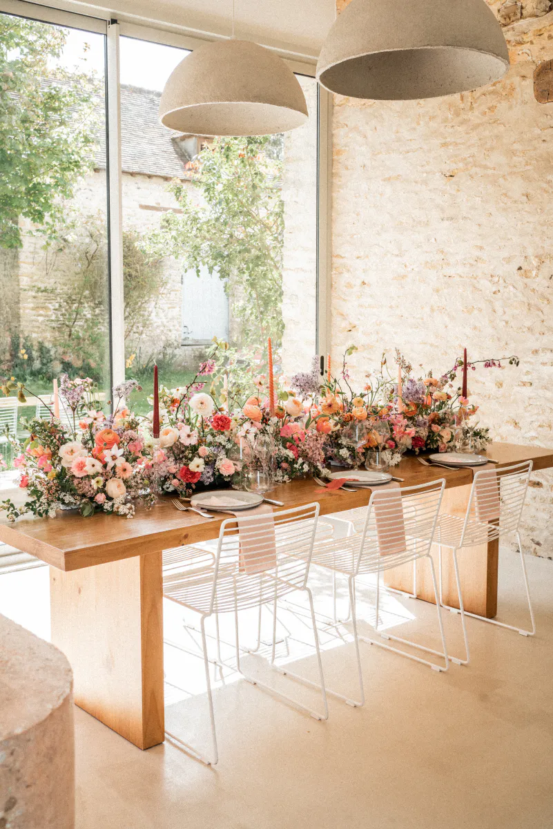Longue table fleurie dans une salle en pierre lumineuse