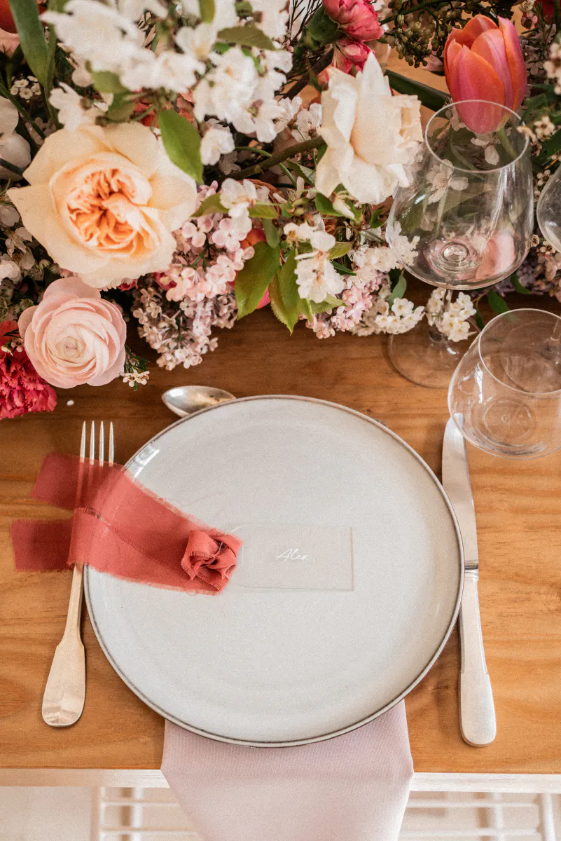 Assiette dressée entourée de roses et de fleurs de saison