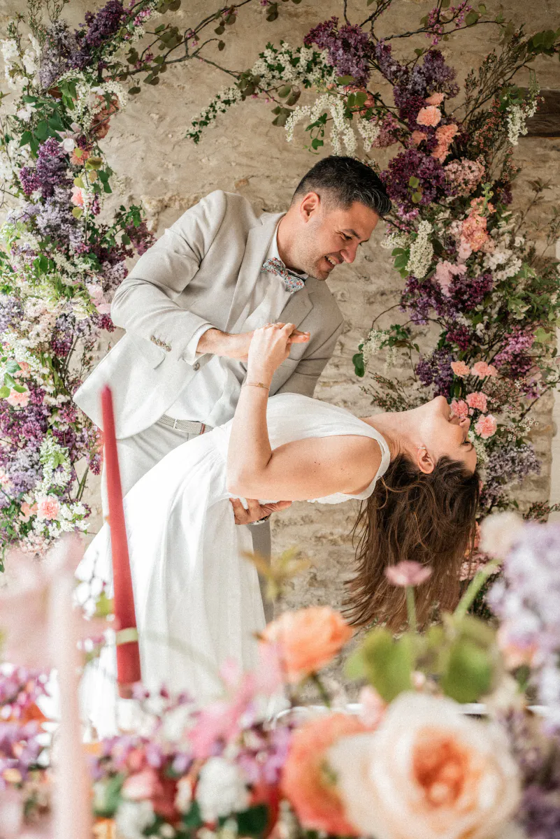 Mariés dansant sous une arche florale