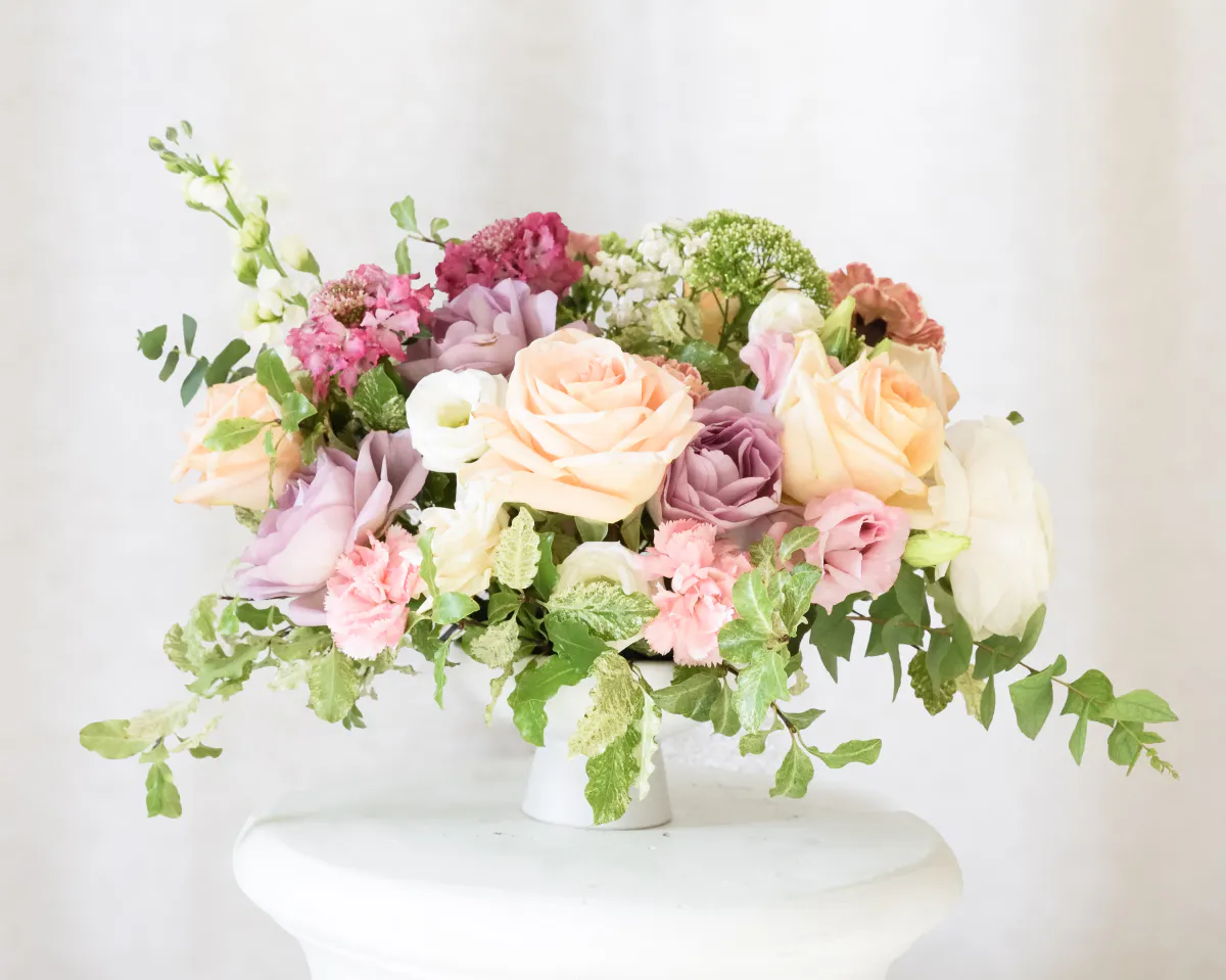 Bouquet de roses et pivoines poudrées sur une colonne blanche