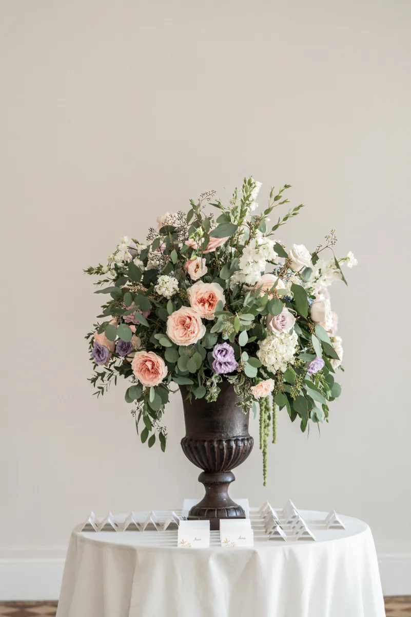Composition florale aux roses poudrées dans une vasque noire, sur une table ronde
