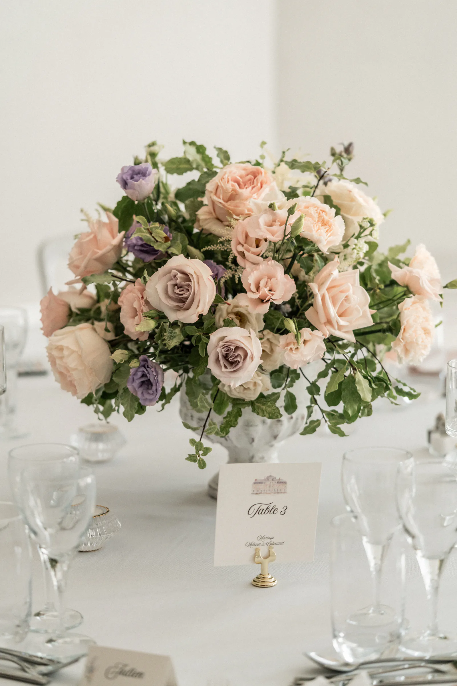 Centre de table généreux de roses pêche et lilas sur une table de réception