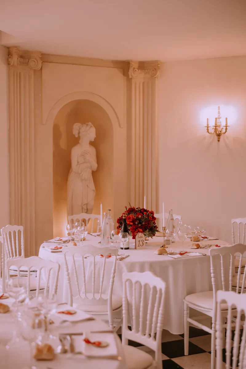 Table ronde fleurie de roses rouges devant une statue en niche