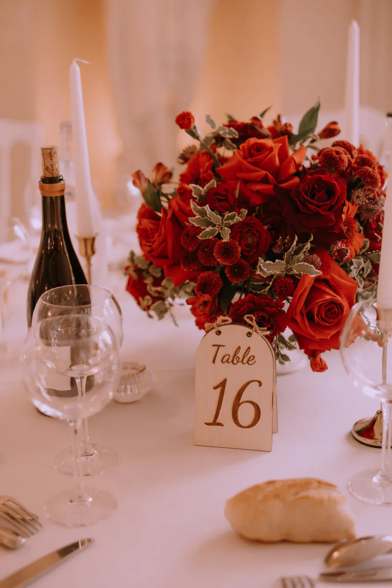 Centre de table de roses rouges et numéro de table calligraphié