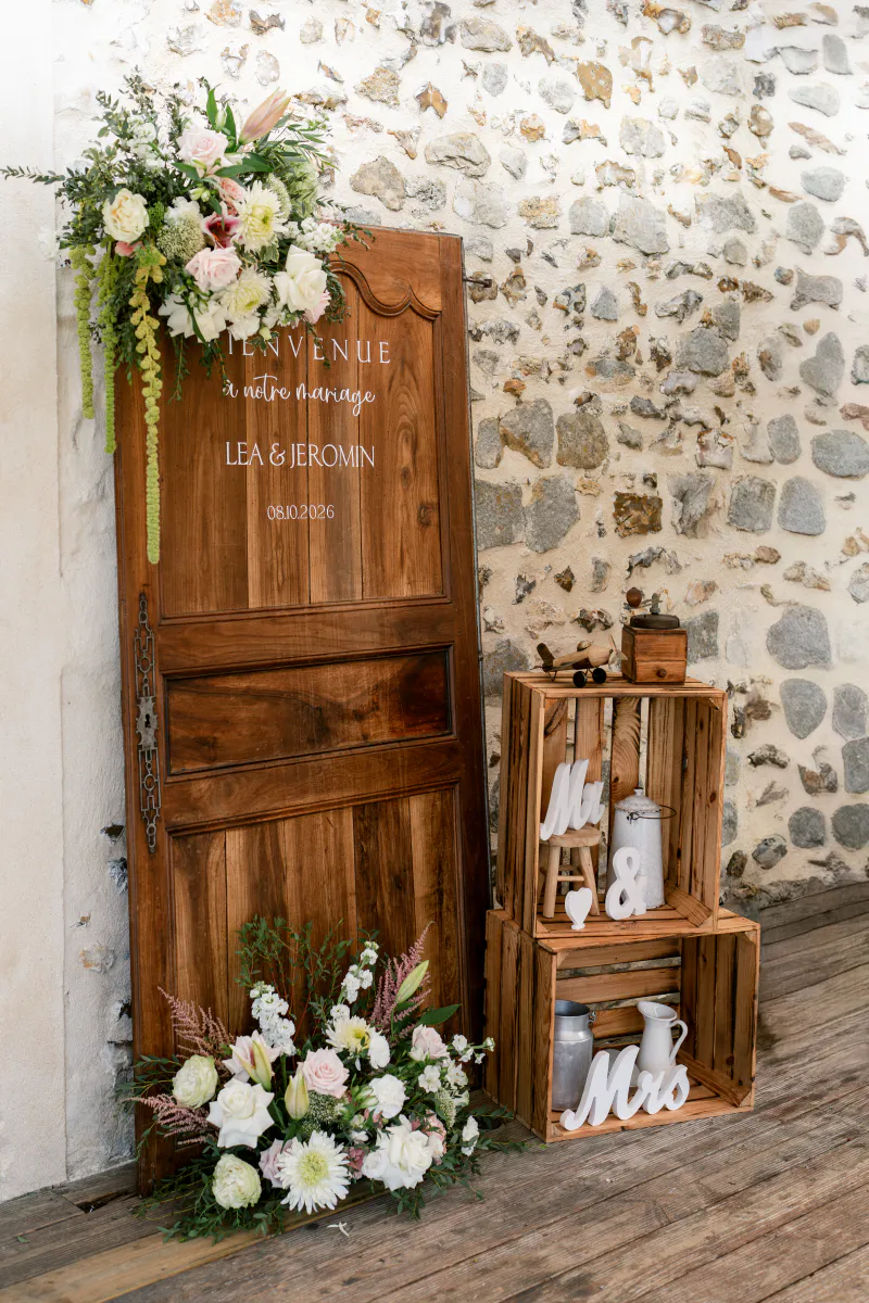 Panneau de bienvenue sur une porte en bois, caisses et bouquets blancs